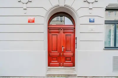 a red door in a white building with an archway at Blueground Žižkov nr University of Economics PRG-36 in Prague