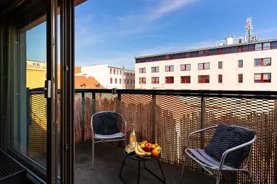 a balcony with two chairs and a bowl of fruit on a table at Tiger Deluxe Suite in Prague