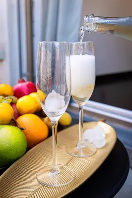 two glasses of white wine on a table with fruit at Tiger Deluxe Suite in Prague