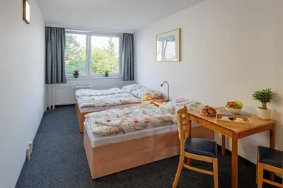 a room with two beds and a table and a desk at Cooliving in Prague