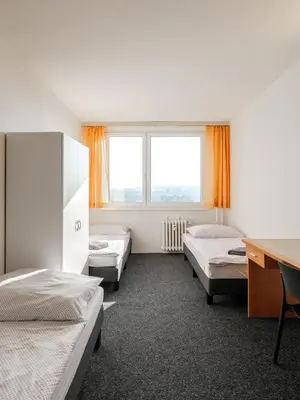 a room with three beds and a desk and two windows at Cooliving in Prague
