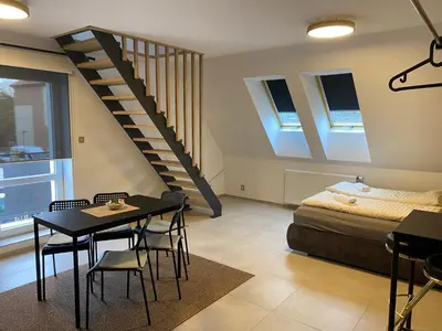 a room with a table and a bed and a staircase at Mezidomí in Budyně nad Ohří