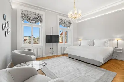 a white bedroom with a bed and a chandelier at Vodickova Luxury Suites in Prague