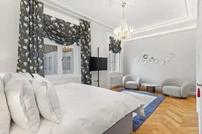 a white bedroom with a large bed and a chandelier at Vodickova Luxury Suites in Prague