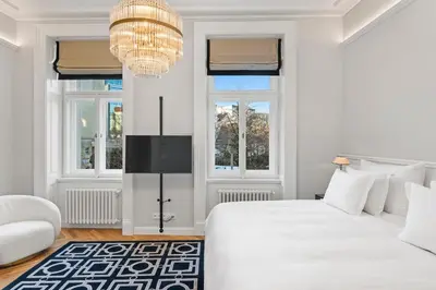 a white bedroom with a large bed and a chandelier at Vodickova Luxury Suites in Prague