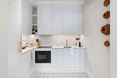 a white kitchen with white cabinets and a sink at Vodickova Luxury Suites in Prague