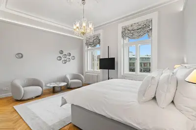 a white bedroom with a bed and two chairs at Vodickova Luxury Suites in Prague