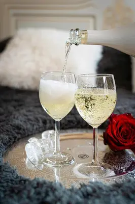 a person pouring white wine into two wine glasses at Victory Deluxe Suite in Prague