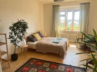 a bedroom with a bed and a large window at Stylový a slunný byt s uměleckým nádechem v blízkosti centra in Prague