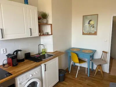 a kitchen with a washing machine and a blue table at Stylový a slunný byt s uměleckým nádechem v blízkosti centra in Prague