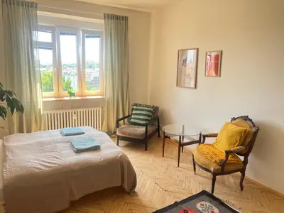 a bedroom with a bed and a chair and a table at Stylový a slunný byt s uměleckým nádechem v blízkosti centra in Prague
