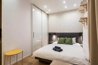 a bedroom with a white bed and a yellow stool at Lighthouse Apartment in Prague
