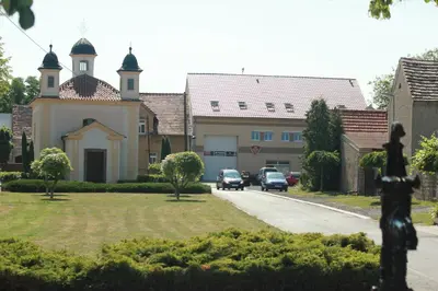 a building with two towers and cars parked on a street at Penzion Piller in Chvalín