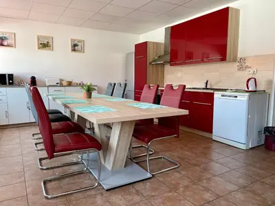 a kitchen with a wooden table and red chairs at Penzion Piller in Chvalín