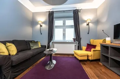 a living room with a black couch and a yellow chair at Apartment Municipal house Prague 1 Old town in Prague