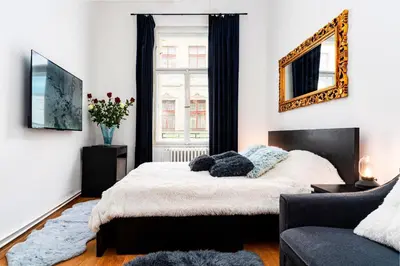 a bedroom with a bed with a mirror and a couch at Black Diamond Suite in Prague