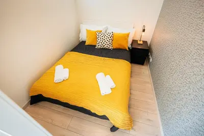 a bedroom with a yellow bed with slippers on it at Centrum Apartments Pstrossova in Prague