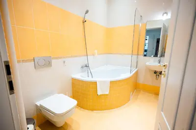 a bathroom with a tub and a toilet and a sink at Centrum Apartments Pstrossova in Prague