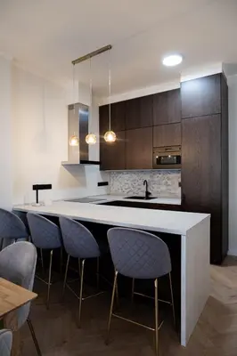 a kitchen with a counter and some blue chairs at Rentero apartment, 4 minutes National Theather, Prague in Prague