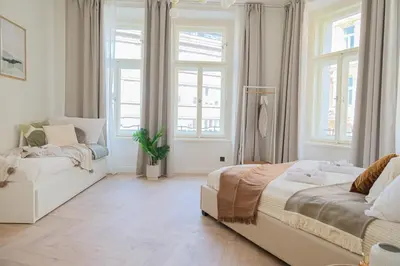 a white bedroom with two beds and windows at Rentero apartment, 4 minutes National Theather, Prague in Prague