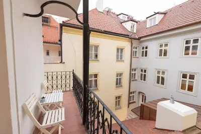 a balcony with two white chairs and a table at Adam's Apartment - Great Price & Best Location in Prague