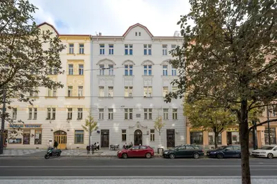 a large white building with cars parked in front of it at Prague Days - One bedroom newly renovated apartment with workspace and Netflix in Prague