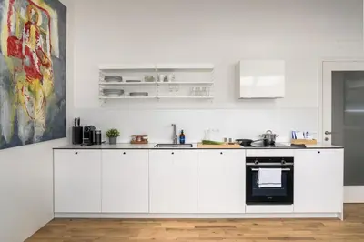a white kitchen with white cabinets and appliances at Prague Days - One bedroom newly renovated apartment with workspace and Netflix in Prague