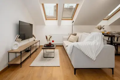 a living room with a white couch and a tv at Prague Days - Two-bedroom Apartment with Workspace and Netflix in Nusle in Prague