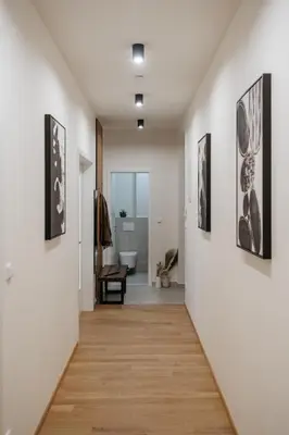 a hallway with white walls and wooden floors and paintings on the walls at Prague Days - Two-bedroom Apartment with Workspace and Netflix in Nusle in Prague