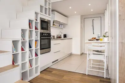 a kitchen with white cabinets and a table and a stool at Prague Days - Cozy Studio with Netflix in Karlín in Prague