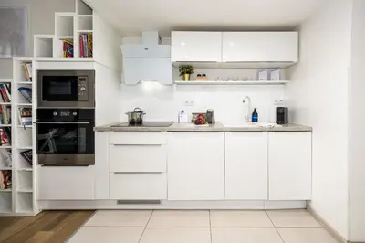 a white kitchen with white cabinets and appliances at Prague Days - Cozy Studio with Netflix in Karlín in Prague
