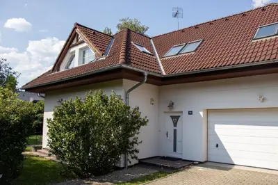 a white house with a brown roof and a garage at Holiday Home Prague Pruhonice in Pruhonice