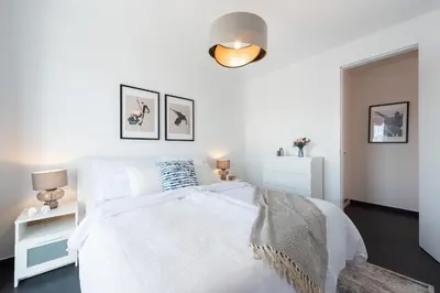 a white bedroom with a white bed and a lamp at All-in Family Apartment Prague in Prague