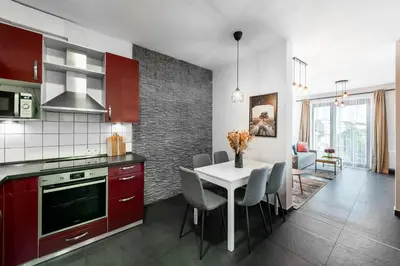 a kitchen with red cabinets and a white table and chairs at All-in Family Apartment Prague in Prague