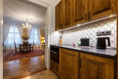 a kitchen with wooden cabinets and a dining room at King's Royal Apartments in City Centre in Prague