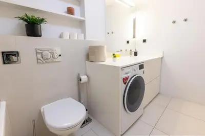 a white bathroom with a toilet and a washing machine at Chic & Central New Town Apartment by Subway in Prague