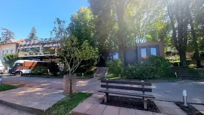a bench in a park with a building in the background at Tenis Cibulka Suites in Prague