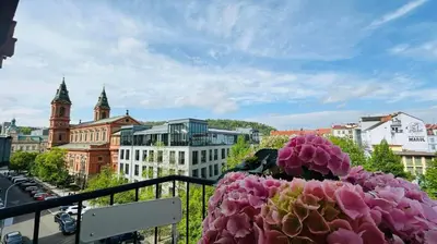 a flower on a balcony with a view of a city at Park View Apartment Anděl in Prague