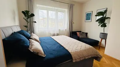 a bedroom with a blue bed and a window at Park View Apartment Anděl in Prague