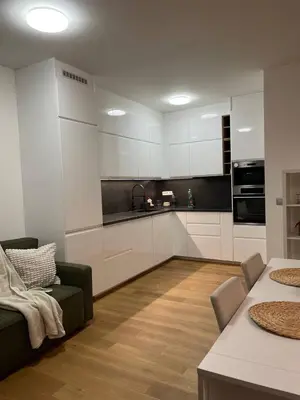 a kitchen with white cabinets and a couch and a table at Serene & Private Garden Oasis in Prague
