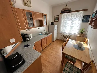 a kitchen with wooden cabinets and a table and a kitchen with a refrigerator at Apartments & Restaurant Tkalcovsky dvur in Prague