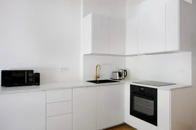 a kitchen with white cabinets and a black appliance at Blueground Vršovice private terrace equipped PRG-8 in Prague