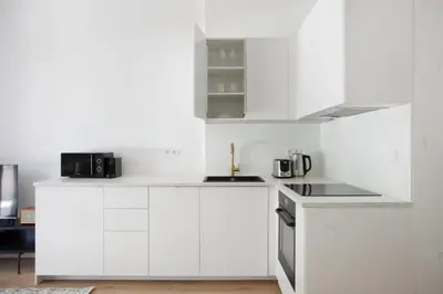 a white kitchen with white cabinets and appliances at Blueground Vršovice private terrace equipped PRG-8 in Prague
