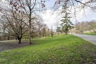 a park with green grass and trees and a road at Blueground Vršovice private terrace equipped PRG-8 in Prague