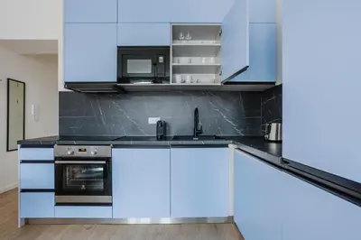 a kitchen with white cabinets and blue appliances at Blueground Prague 2 renovated Náměstí Míru PRG-33 in Prague