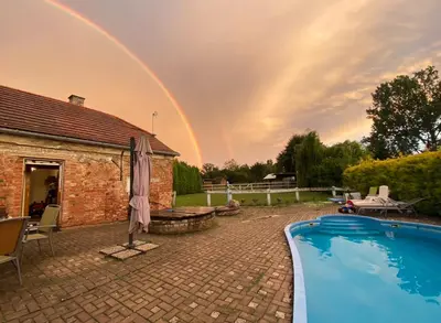 a rainbow over a house with a swimming pool at Domeček na samotě in Terezín