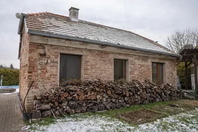 a brick house with a pile of fire wood at Domeček na samotě in Terezín