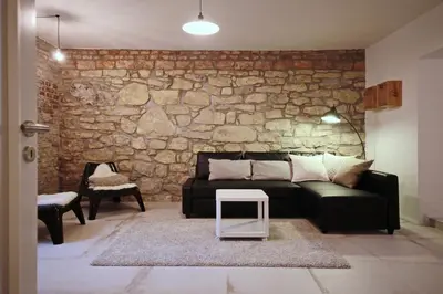 a living room with a black couch and a stone wall at Apartment Kosatcová in Prague