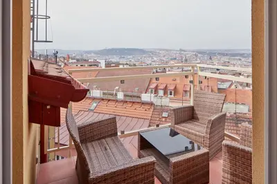 a balcony with chairs and a table on a roof at Prague Days - Deluxe Loft with View in Vinohrady in Prague