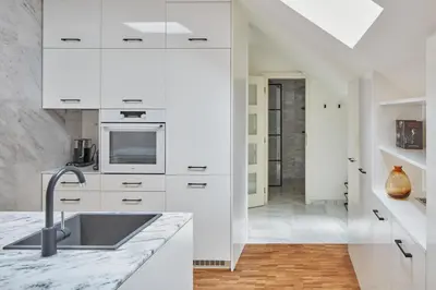 a kitchen with white cabinets and a sink at Prague Days - Deluxe Loft with View in Vinohrady in Prague
